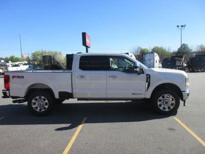 Ford F-350 pickup truck side view in a parking lot, white crew cab with chrome wheels and Tundra-style bed rails.