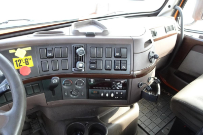 Dashboard of Volvo truck cab showing array of switches and controls, steering wheel, and key ignition area.