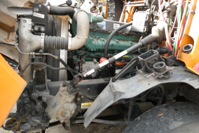 Volvo VN/M64T truck engine bay showing green engine block, hoses, belts, and surrounding components in service area.