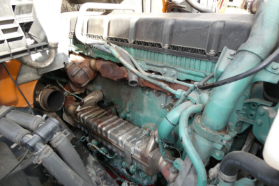 Volvo VNM64T engine bay showing green engine block, intake manifold, hoses, and surrounding components in a truck engine compartment.