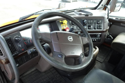 Volvo truck cab interior with steering wheel and dashboard; visible controls and vents.