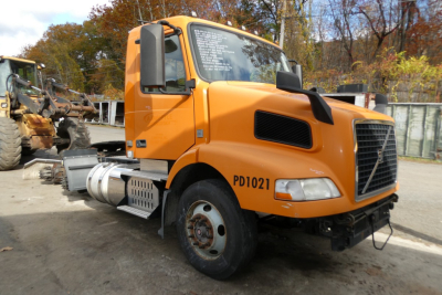 Orange Volvo Cab-Over in-service truck with PD1021 stenciled on door and windshield text; front bumper and engine bay visible.
