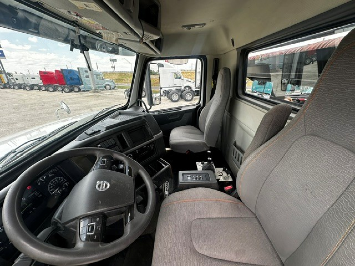 Cab interior of a 2020 Volvo VHD roll-off truck showing steering wheel, driver seat, and front passenger seat with center console and instrument panel.