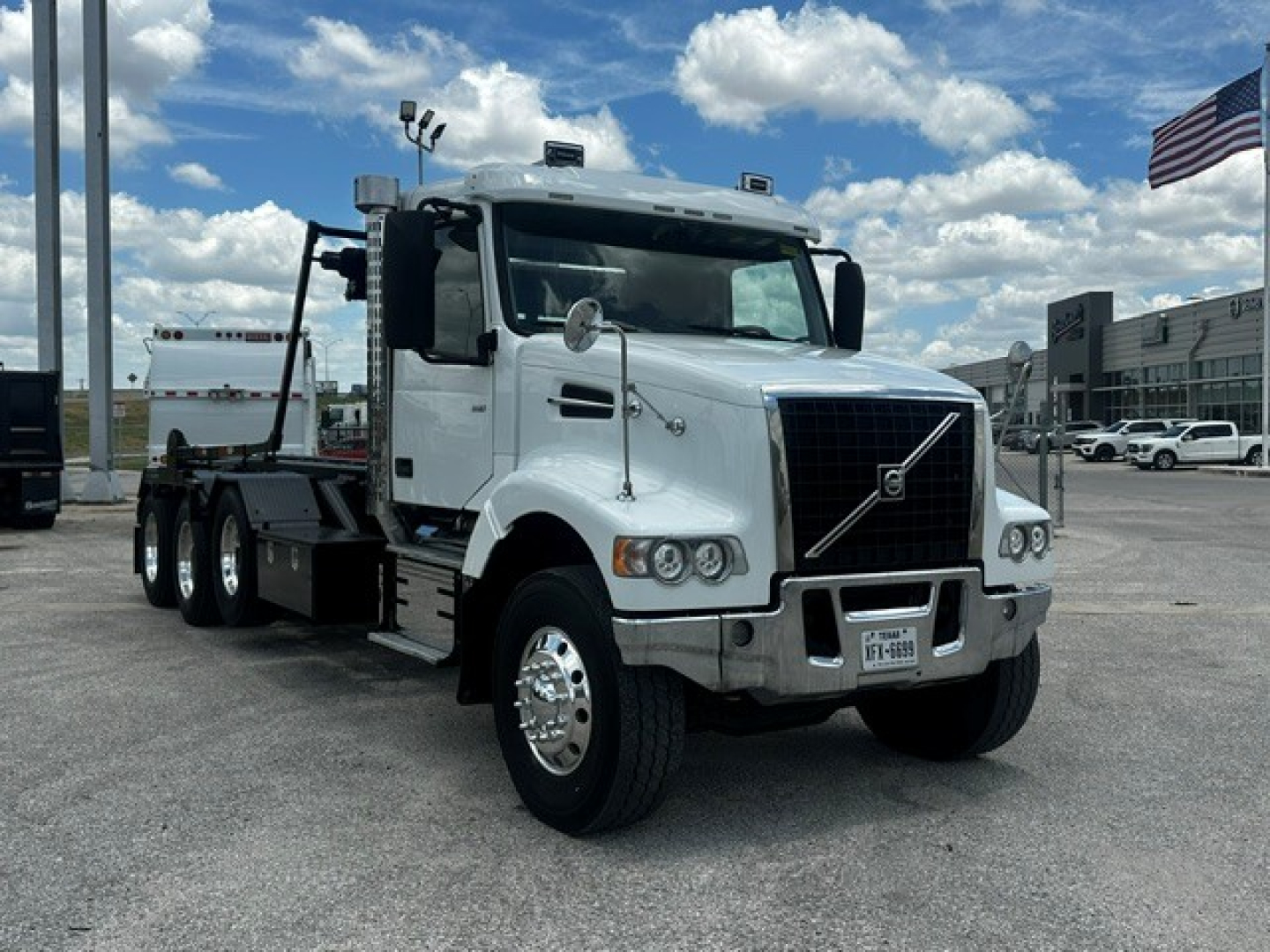 White 2020 Volvo VHD roll-off truck, front three-quarter view, with chrome grille, large bumper, and dual rear axles.