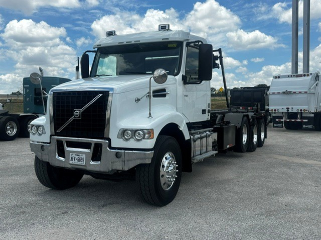 White 2020 Volvo VHD rolloff truck cab view showing front grille, headlights, side mirrors, and dual rear axles.