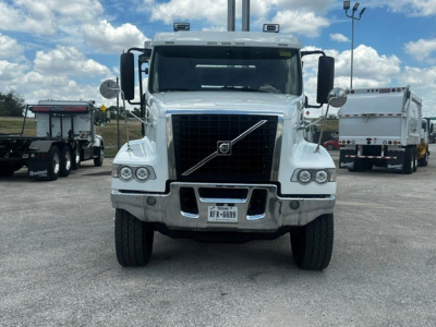 Front view of a white 2020 Volvo VHD roll-off truck showing the grille with Volvo badge, large bumper, and Texas license plate.