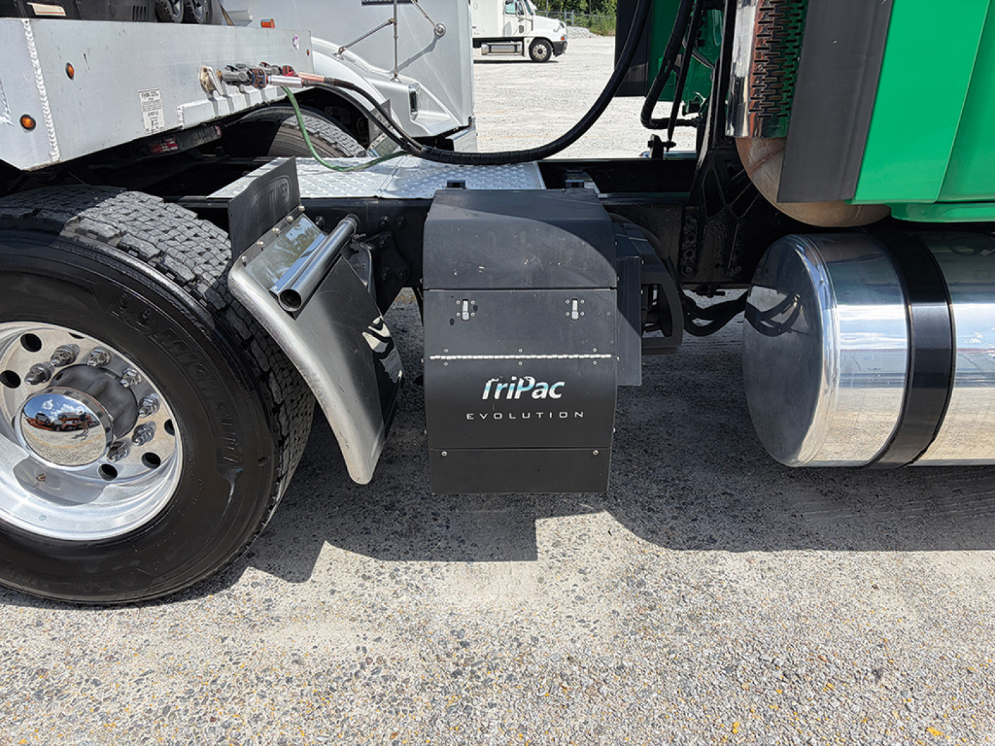 Truck side showing fuel tank, wheel, and a black TriPac Evolution battery box with TRI-PAC Evolution branding near the cab on a Freightliner Cascadia.