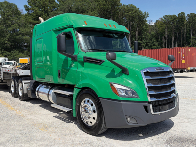 Truck cab and sleeper of a green Freightliner Cascadia 126 tractor from a front-right angle, showing chrome fuel tanks, black grille, and wheel area.