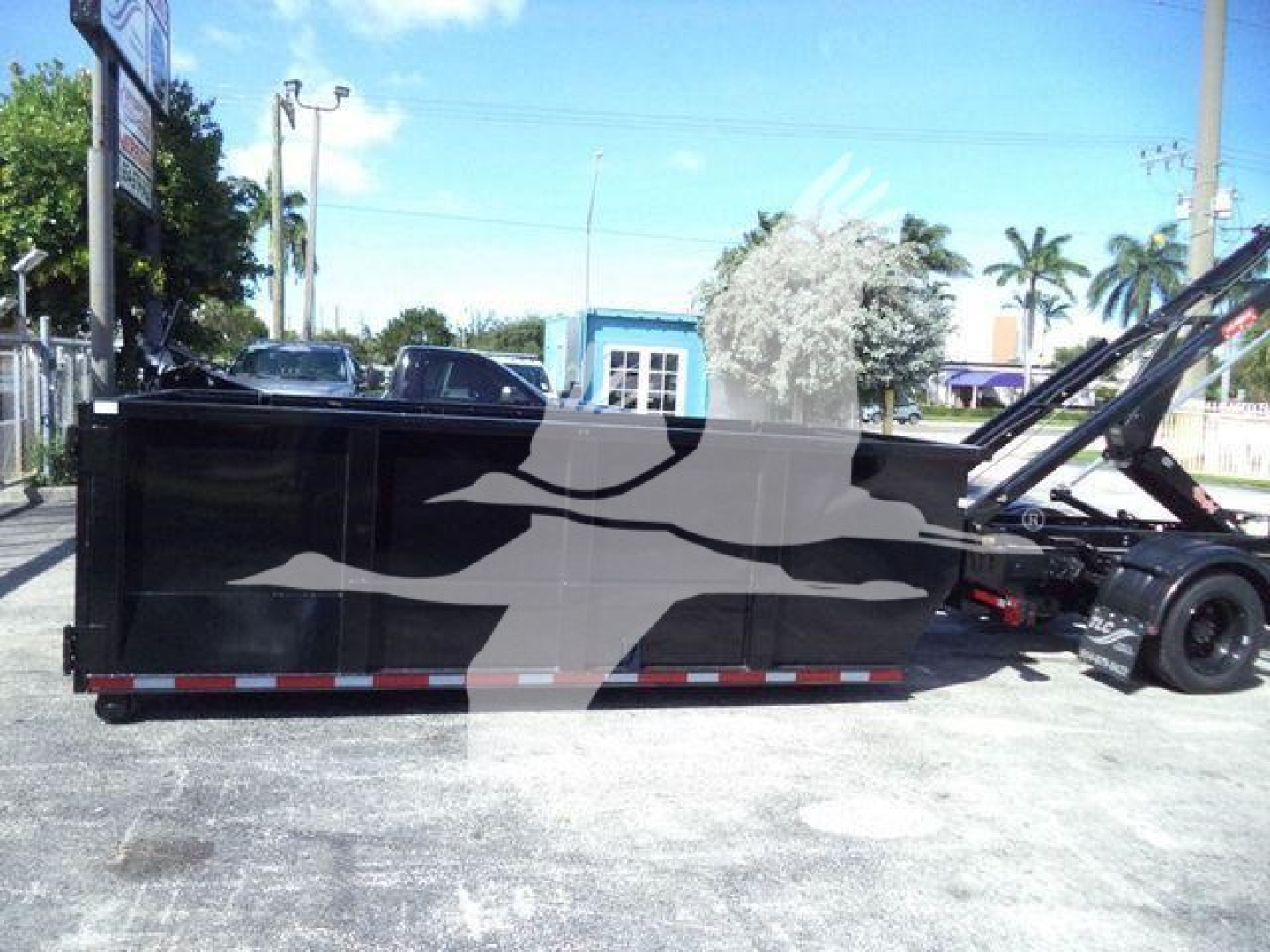 Side view of a 2023 Chevrolet Silverado 6500HD roll-off truck bed in a dealership lot.