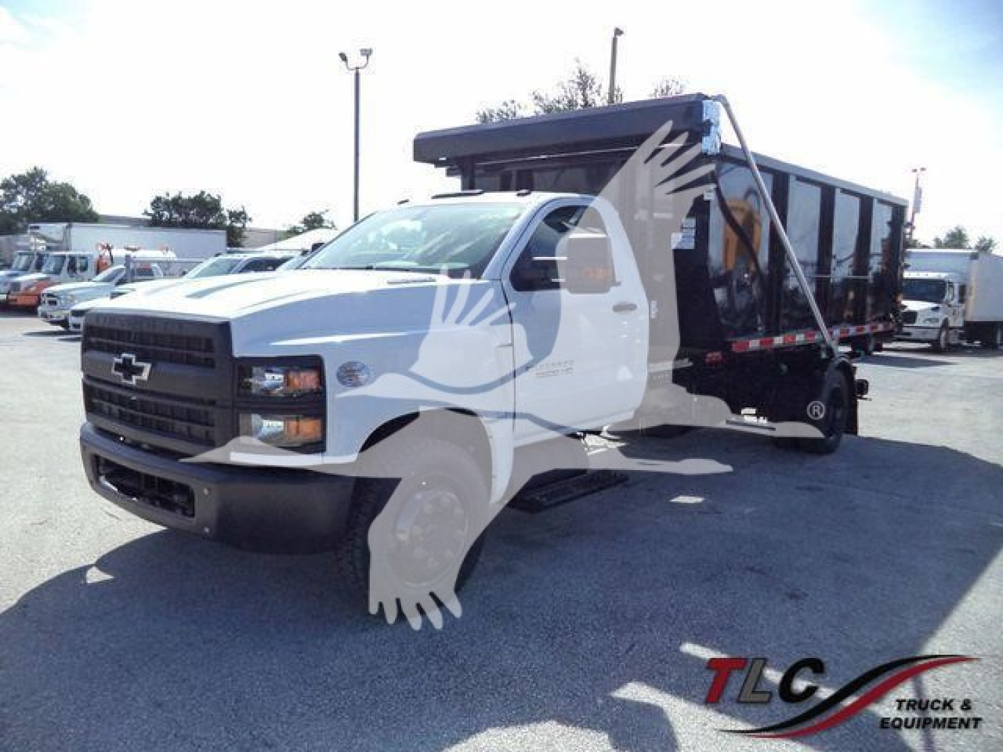 2023 Chevrolet Silverado 6500HD rolloff dump truck with white cab and black dump body, parked in lot. Stock number J05565FM visible. TLC Trucks & Equipment watermark.