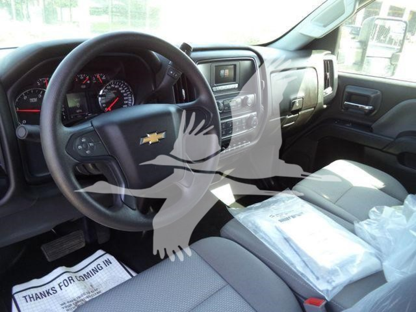 Interior of a 2023 Chevrolet Silverado 6500HD cab showing steering wheel with Chevy logo and dashboard controls.