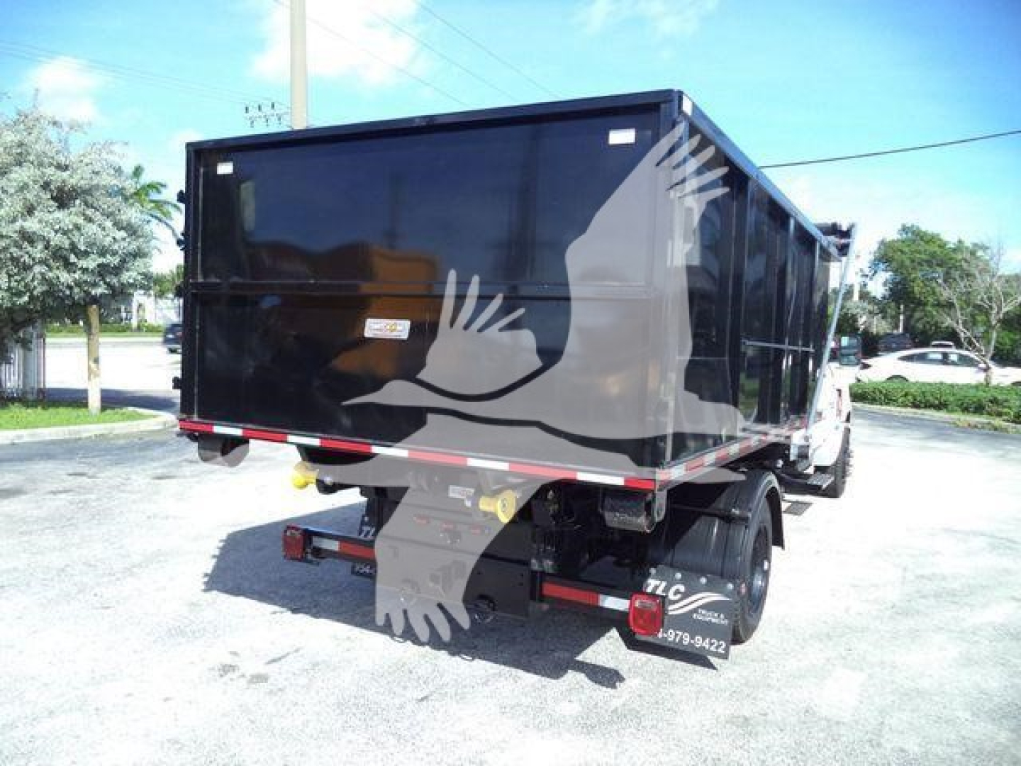 Truck rear view showing a black dump bed/roll-off container on a Chevrolet Silverado HD chassis.