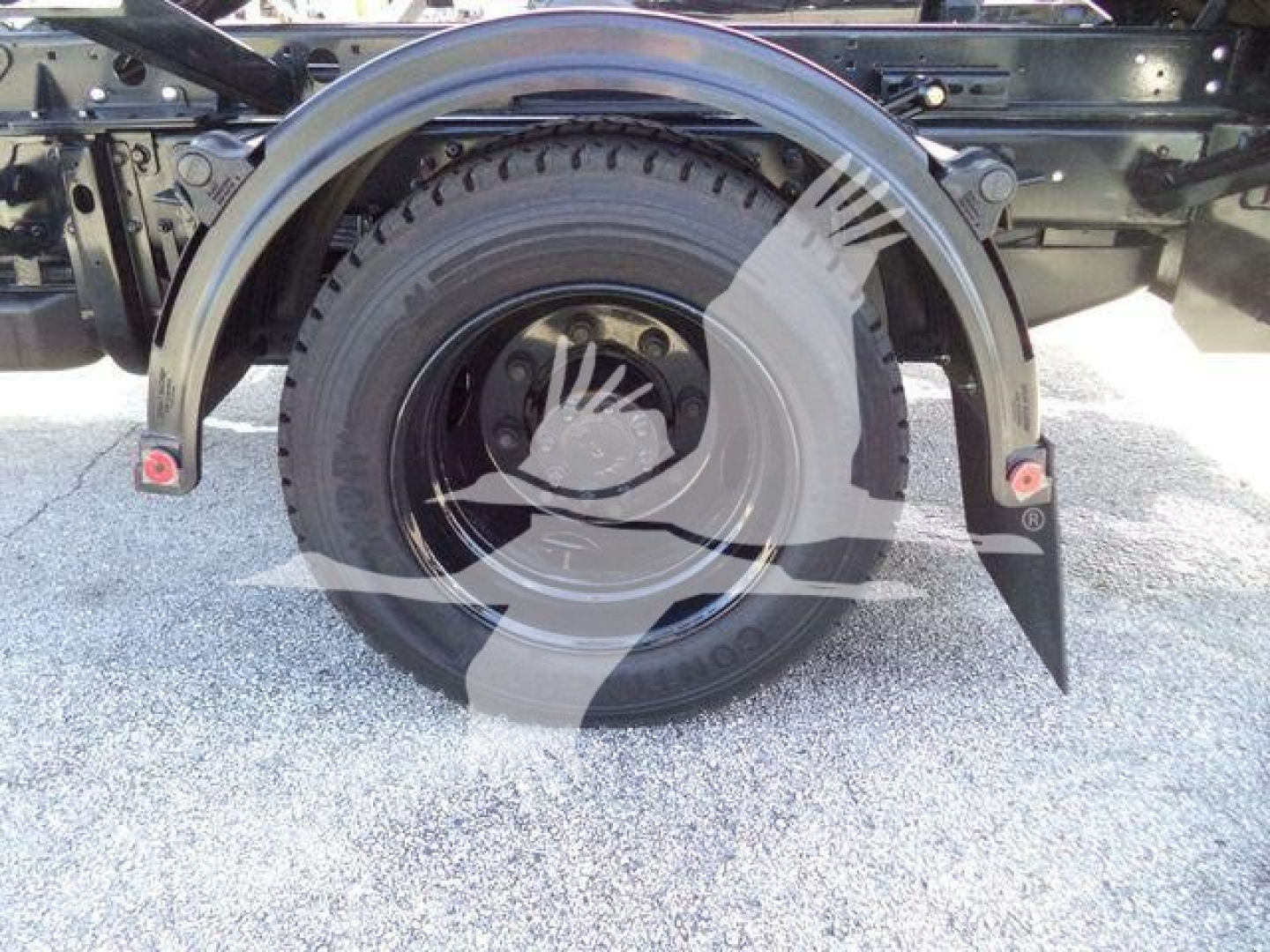 Truck wheel and fender assembly on a 2023 Chevrolet Silverado 6500HD roll-off truck showing the rear wheel and mud flaps.