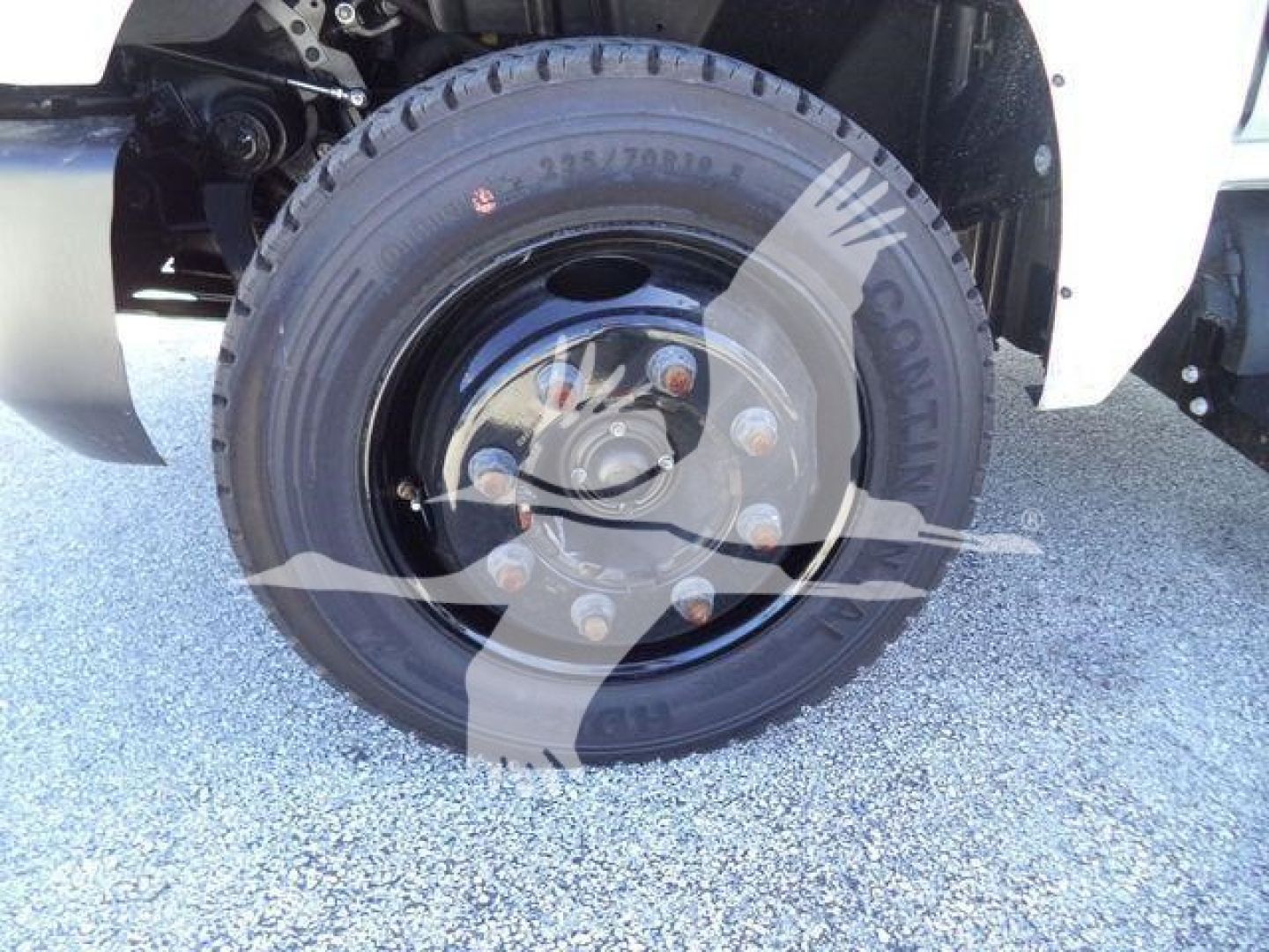 Wheel and tire close-up of a 2023 Chevrolet Silverado 6500HD roll-off truck showing the front wheel with lug nuts and tire markings