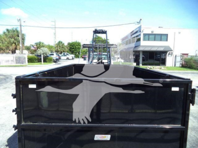 Truck bed of a 2023 Chevrolet Silverado 6500HD roll-off truck showing a black dump body with rear doors closed, parking lot in background.