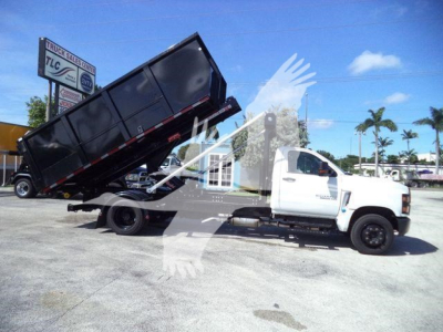 Truck bed dump in raised position on white Chevy Silverado 6500HD roll-off truck with black dump body