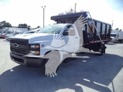 Front-left view of a white 2023 Chevrolet Silverado 6500HD roll-off truck with a black dumped bed, showing cab and chassis.