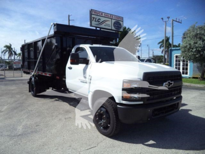 Truck in lot showing a white 2023 Chevrolet Silverado 6500HD roll-off dump body side view.