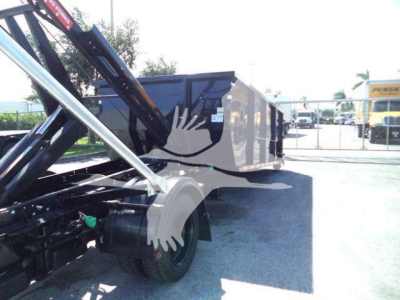 Truck component view showing a roll-off bed with hydraulic arms and a wheel; no legible text visible on components.