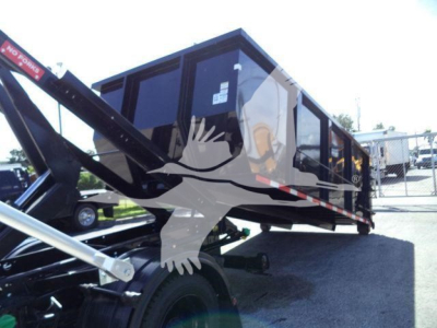 Truck bed with a roll-off dumpster on a Chevrolet Silverado 6500HD chassis showing hydraulic arm and black dump body.