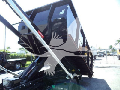 Truck bed tilt/roll-off hoists on a 2023 Chevrolet Silverado 6500HD loader with hydraulic arms and container in raised position, stock J05565FM.