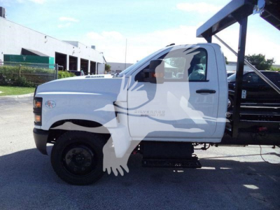 Truck side profile showing white Chevrolet Silverado 6500HD with roll-off body and black wheel/rim.