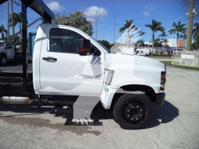 Truck cab side view showing Silverado 6500HD badge and front wheel with black rim in a roll-off truck setup.