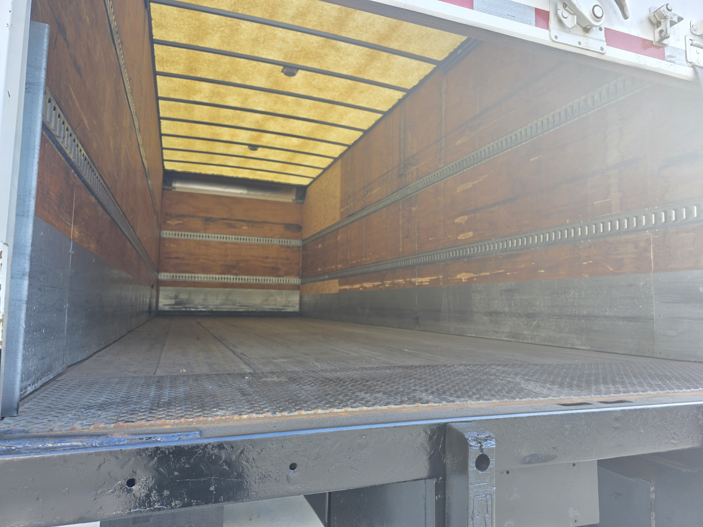 Peterbilt 337 box truck interior cargo area showing empty metal floor and side rails with yellow translucent ceiling.