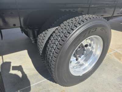 Truck wheel and front fender area showing dual rear tires, polished aluminum rim, and heavy-duty tread on the 2020 Peterbilt 337.