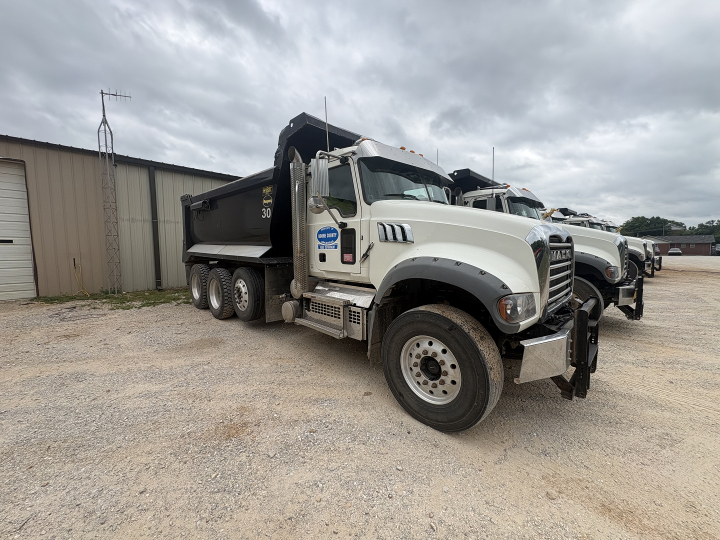 Dump truck showing Mack GR84F cab and white body with black dump bed