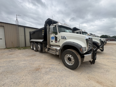 Dump truck showing Mack GR84F cab and white body with black dump bed
