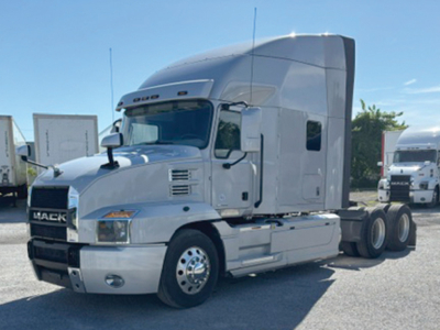 Truck cab of a white 2022 Mack Anthem tractor in-service showing aerodynamic sleeper with elevated roof and front grille with Mack logo.