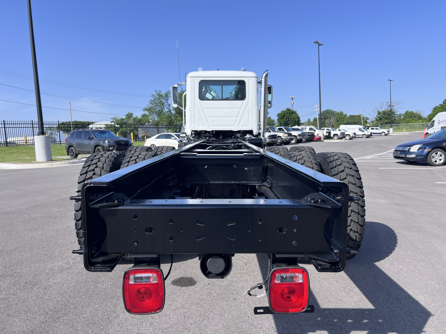 Back view of a 2026 Mack GR64B cab and chassis showing rear chassis frame and dual rear tires with taillights.