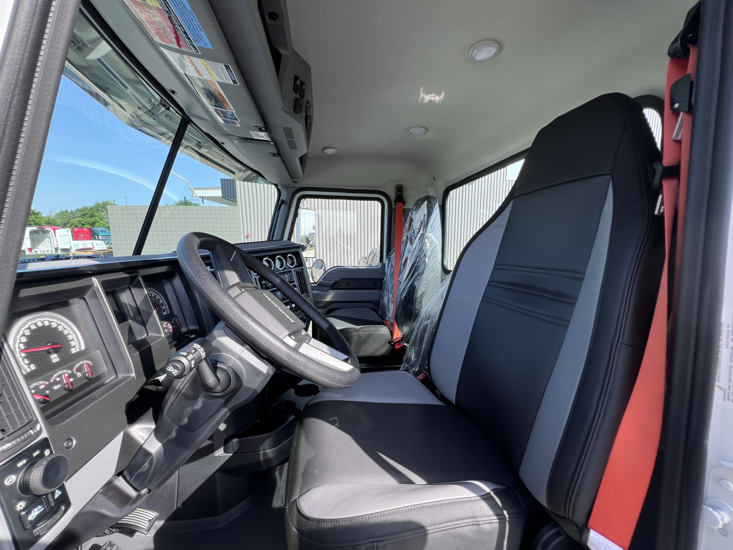 Cab and chassis interior of a 2026 Mack GR64B showing driver seat, steering wheel, dashboard instruments, and front passenger seat.