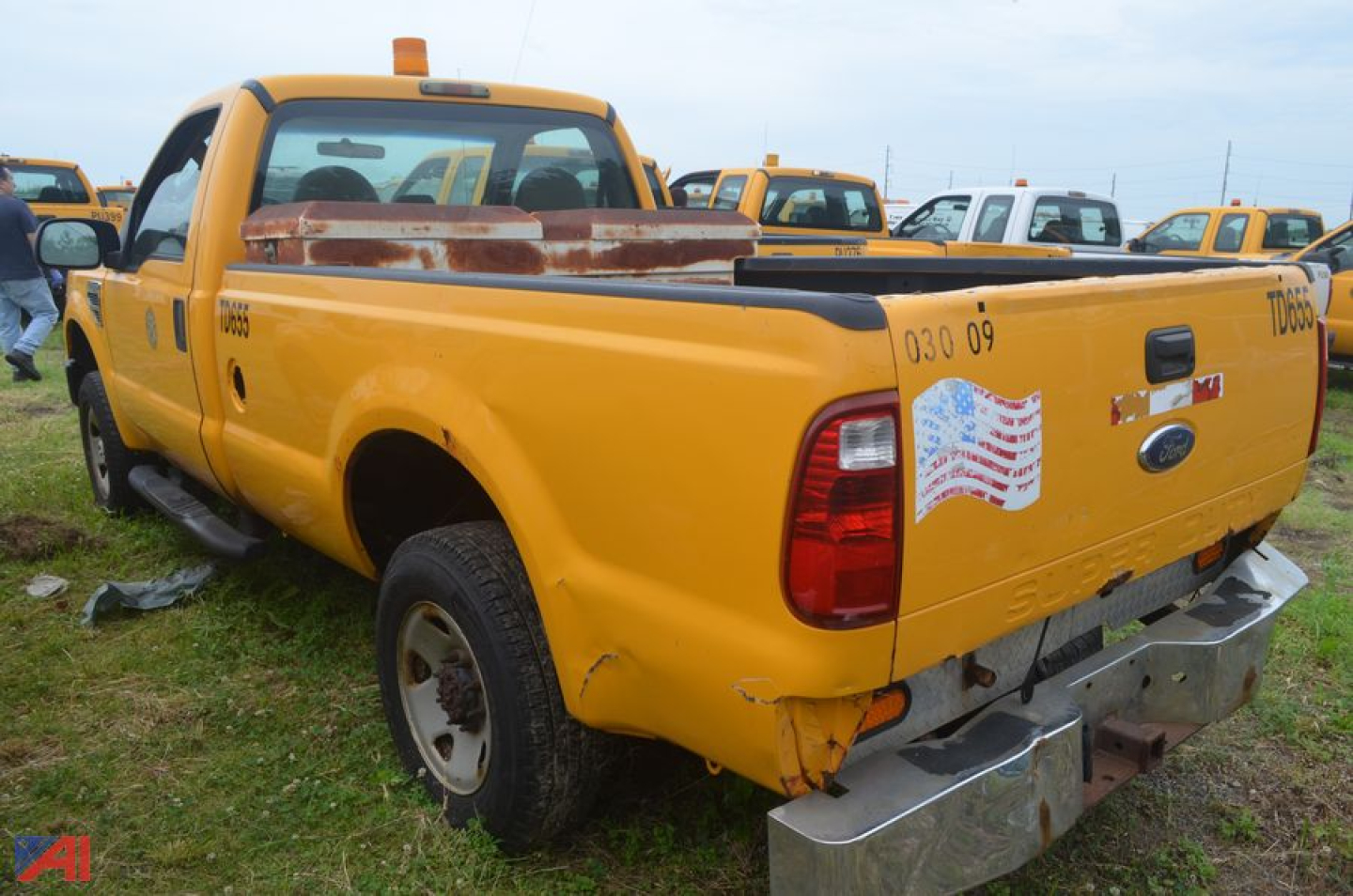 Ford F-250 Super Duty dump truck rear view showing tailgate and bumper with damaged area and sticker.