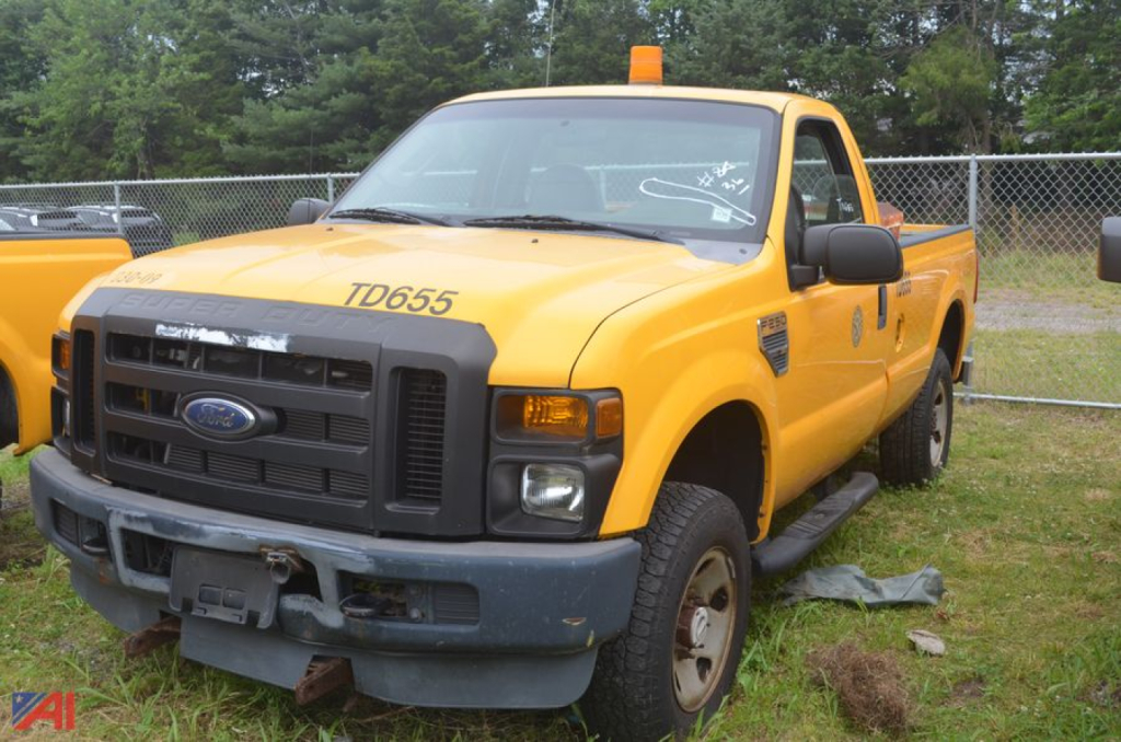 Ford F-250 Super Duty dump truck in yellow with TD655 decal on hood, front bumper guard, and cab with orange beacon light.