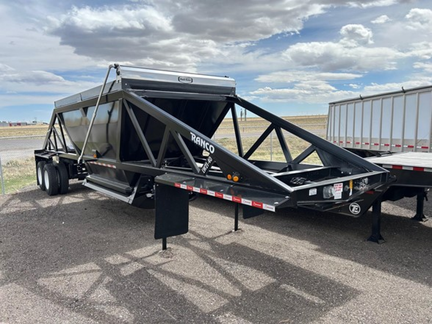 Ranco Versa Vale dump trailer in serviceable condition showing triangular truss frame, dual-axle tandem wheels, and front hitch with RAC hood.