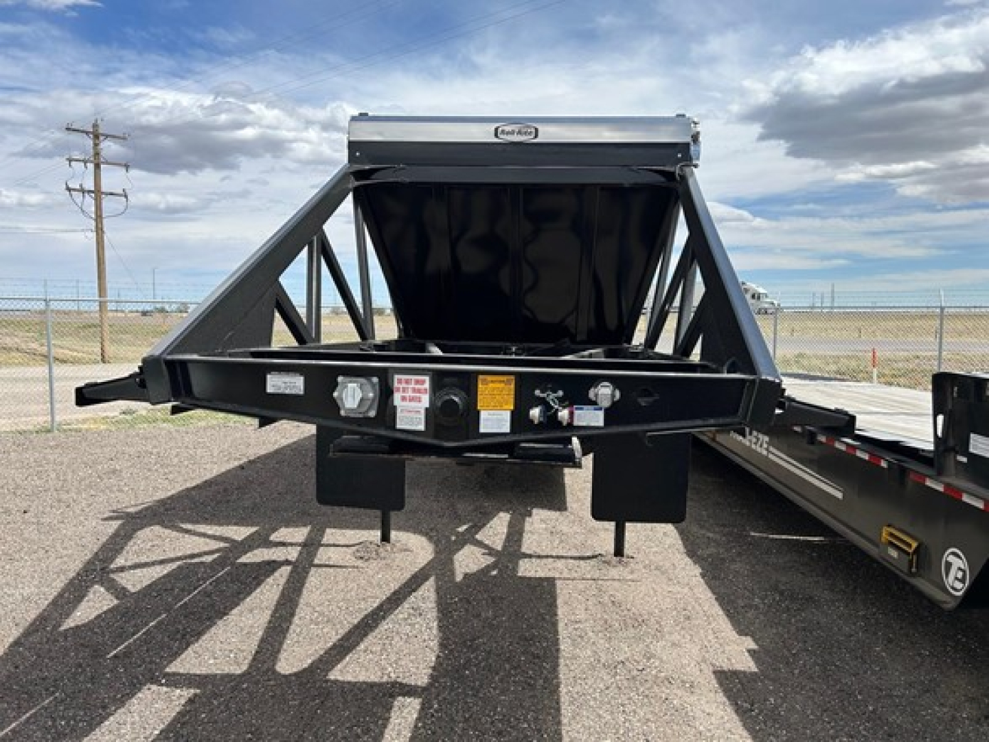 Ranco Versa Vale dump trailer A-frame hitch showing front loading area with signs and connectors on the frame.