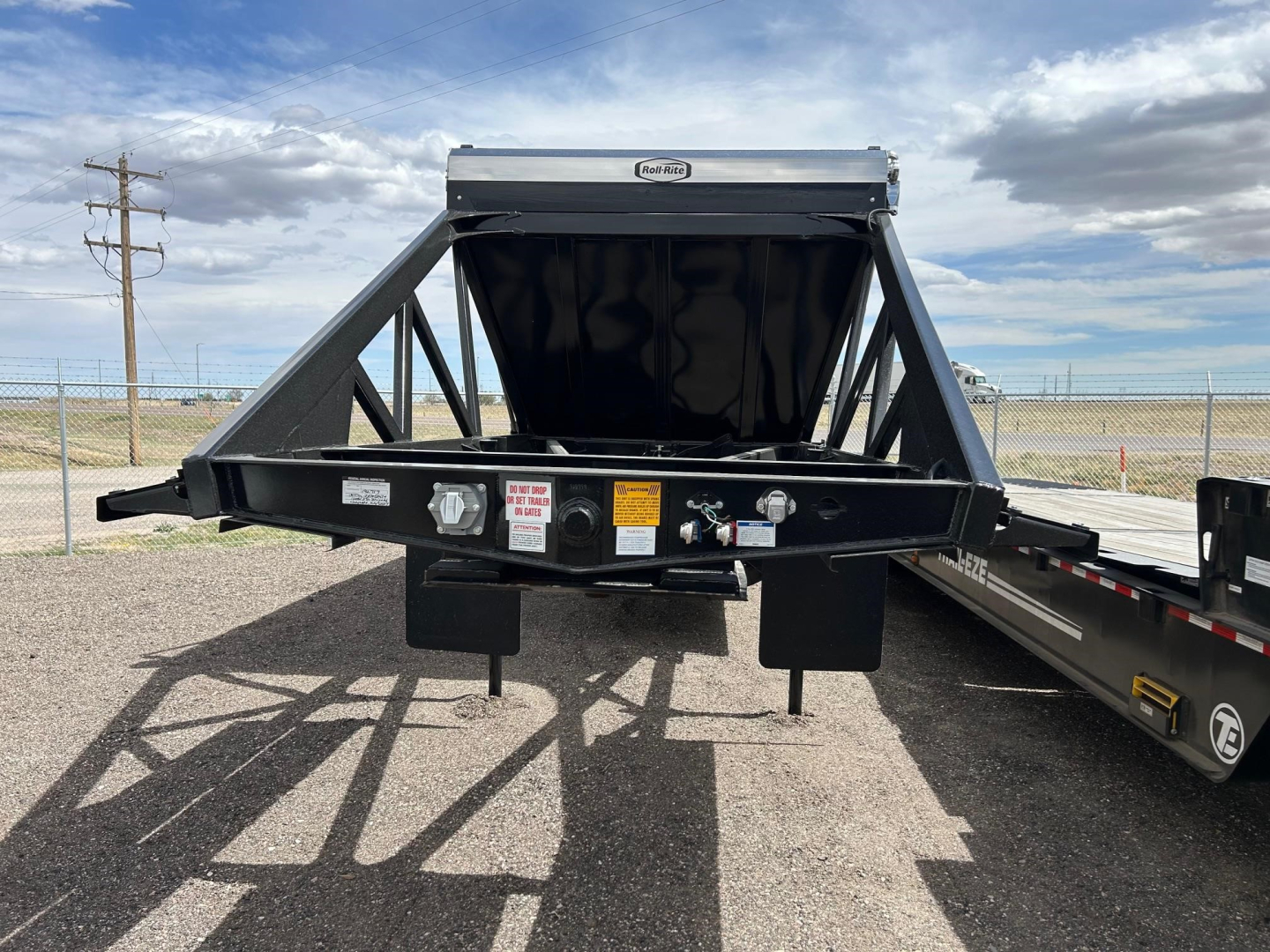 Ranco Versa Vale dump trailer hitch/view showing front of trailer with black steel frame and hopper, VIN and labels on tongue.