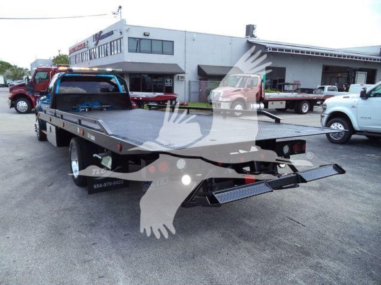 Flatbed tow truck in a lot showing a 2022 Ram 5500 SLT used with a long black steel rollback bed and ramps.