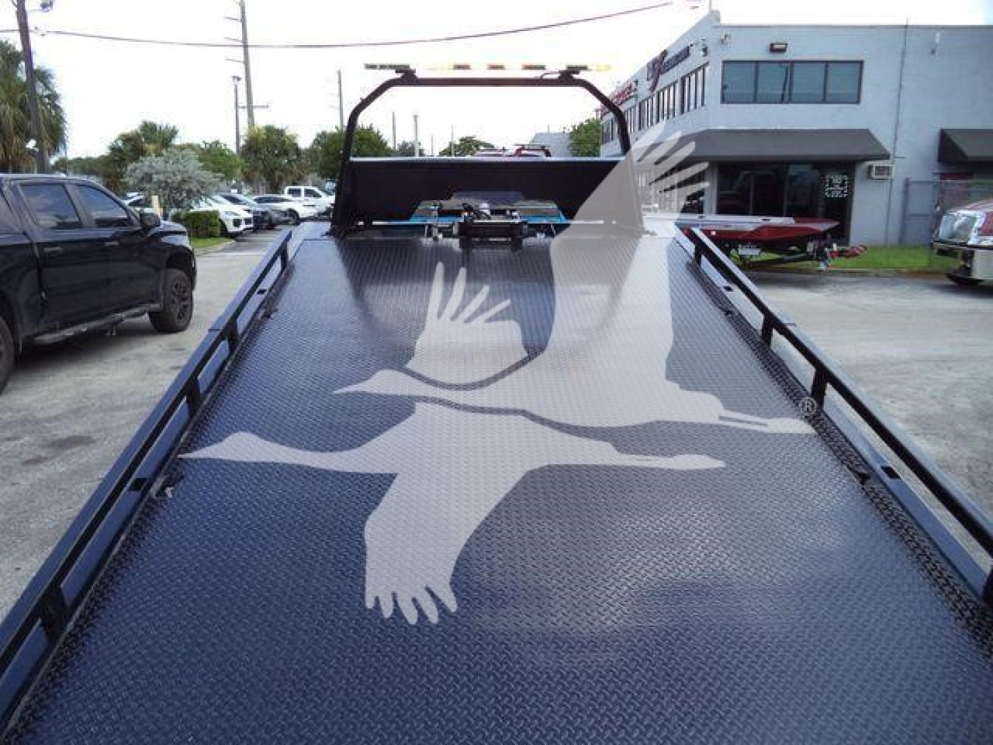 Truck bed of a 2022 Ram 5500 SLT rollover tow truck showing a black diamond plate bed with a white gull image and cabin in background.