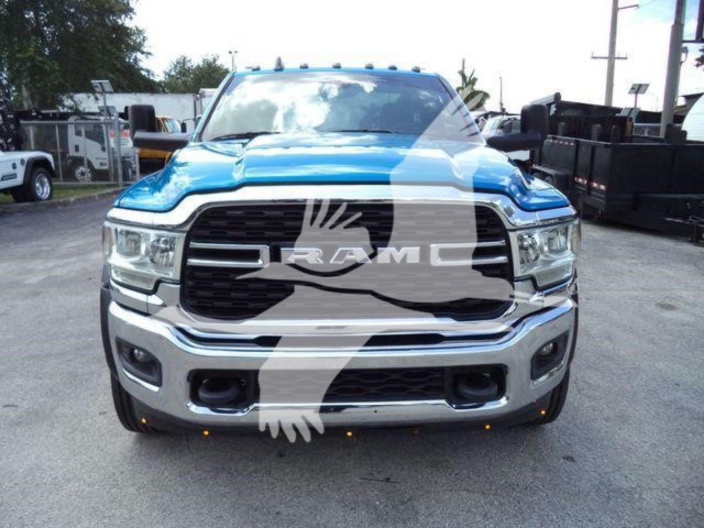 Front view of a blue 2022 Ram 5500 truck with large chrome grille, RAM emblem, and bumper guards in a dealership lot.
