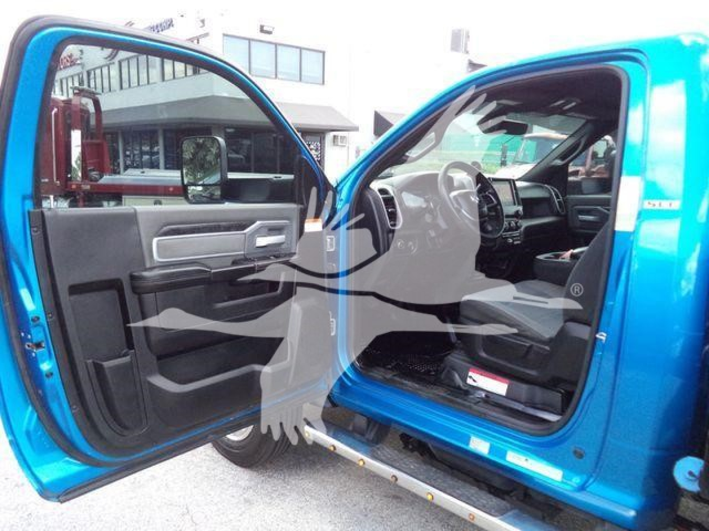 Interior view of a blue Ram 5500 truck with both front doors open, showing the driver's seat, steering wheel, and dashboard.