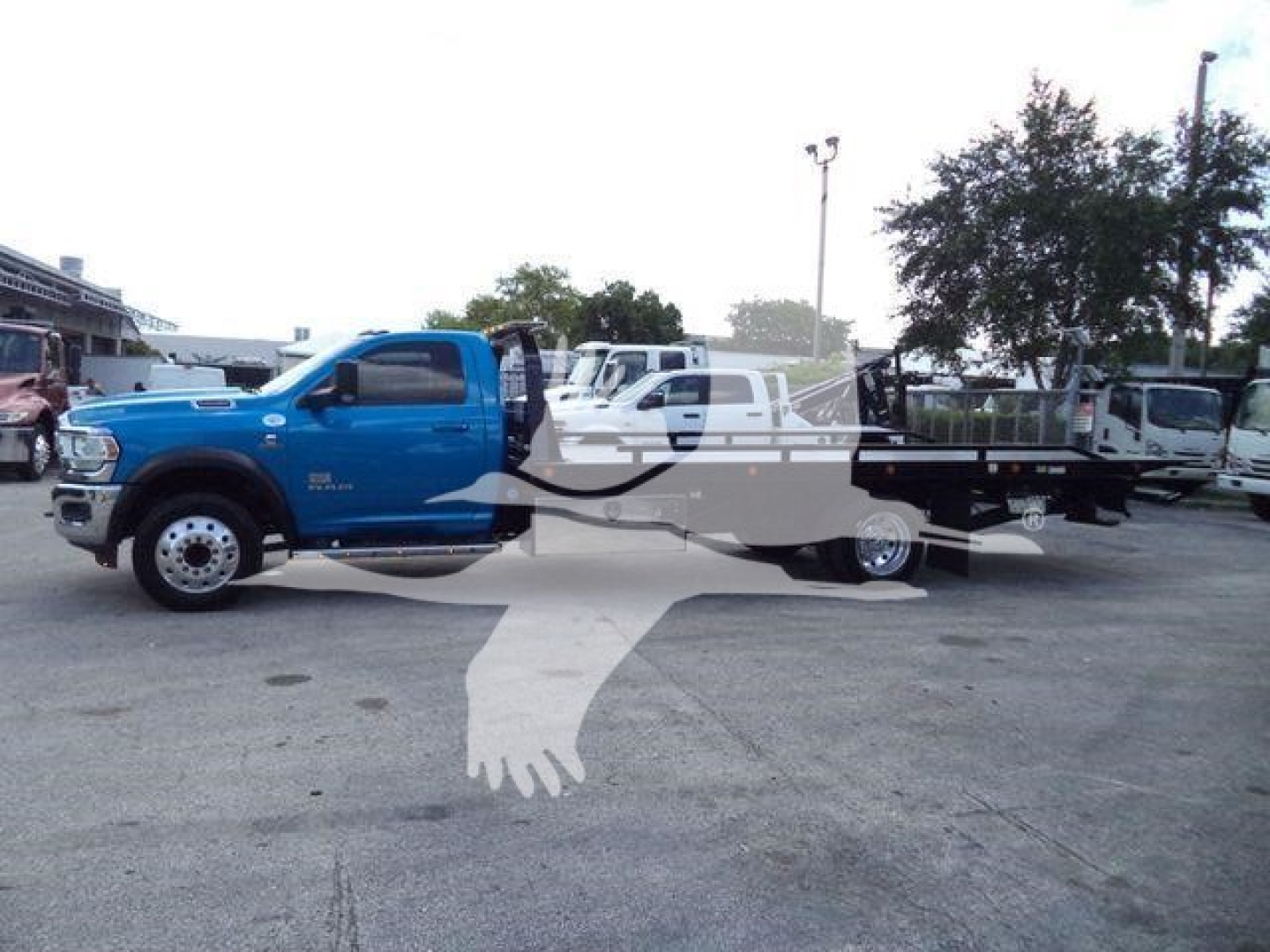 Blue Ram 5500 heavy-duty tow truck/rollback body in a parking lot with a long flatbed.