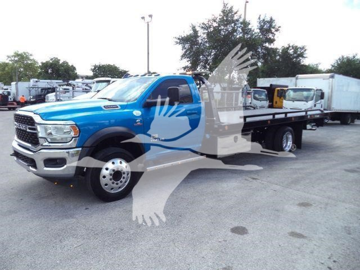 Ram 5500 rollback tow truck blue crew cab front-left view with flatbed in a dealership lot