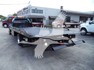Flatbed tow truck in a lot showing a 2022 Ram 5500 SLT used with a long black steel rollback bed and ramps.