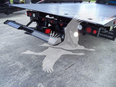 Ram 5500 rollback tow truck bed rear with hydraulic lift and safety lights. Platform steel deck with textured surface and rear step / bumper. Visible taillights and reflective markings.