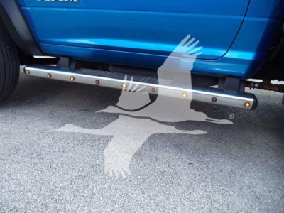 Truck side undercarriage step bar with round yellow reflectors visible under blue Ram 1500/5500 pickup.