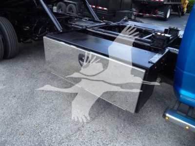 Flat metal toolbox mounted under the rear of a Ram 5500 truck bed, with surrounding chassis and blue step, visible on workshop lot.