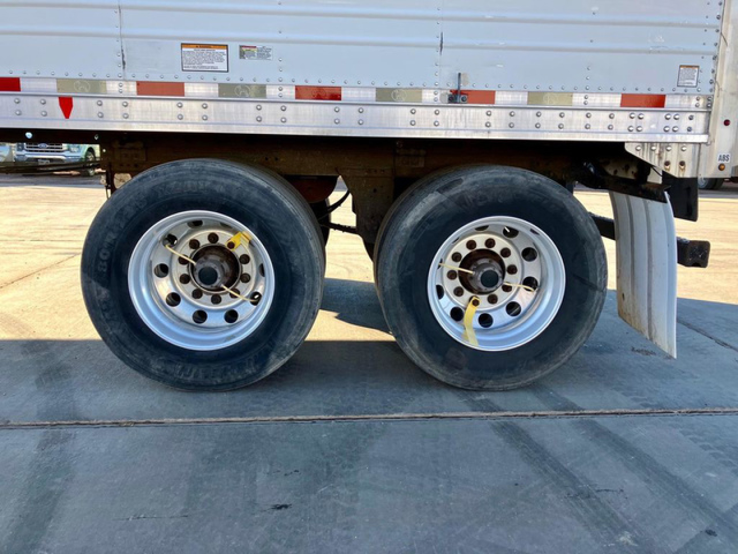 Great Dane reefer trailer wheel assembly showing dual rear axles with wheel rims and tires, partial side panel with reflective tape and stickers.